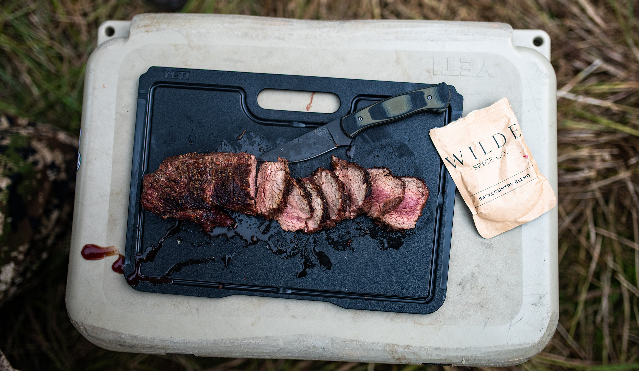Wild game cooked in the field resting on a cooler 